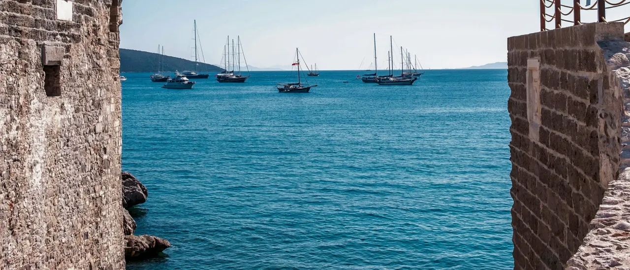 Gulets at anchor in the bay, seen between two stone walls of Bodrum Castle